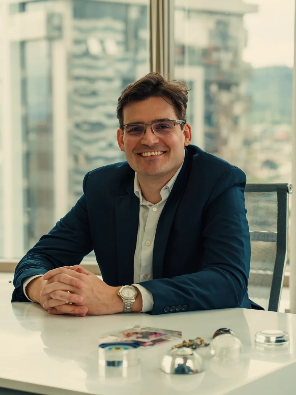 Dr. Alexandre Antonaccio sorrindo, sentado à mesa do consultório